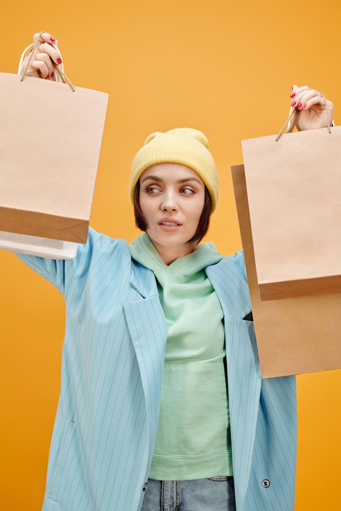 why-choose-us Stylish woman in a bright outfit holding shopping bags against a yellow background.