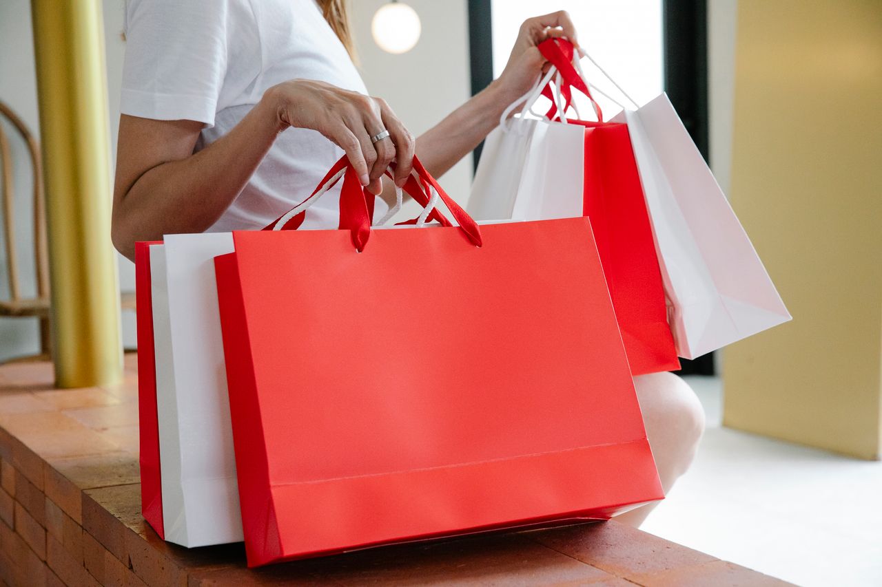 services-03 Side view of crop anonymous female buyer in white t shirt sitting on bench with many shopping bags in daylight