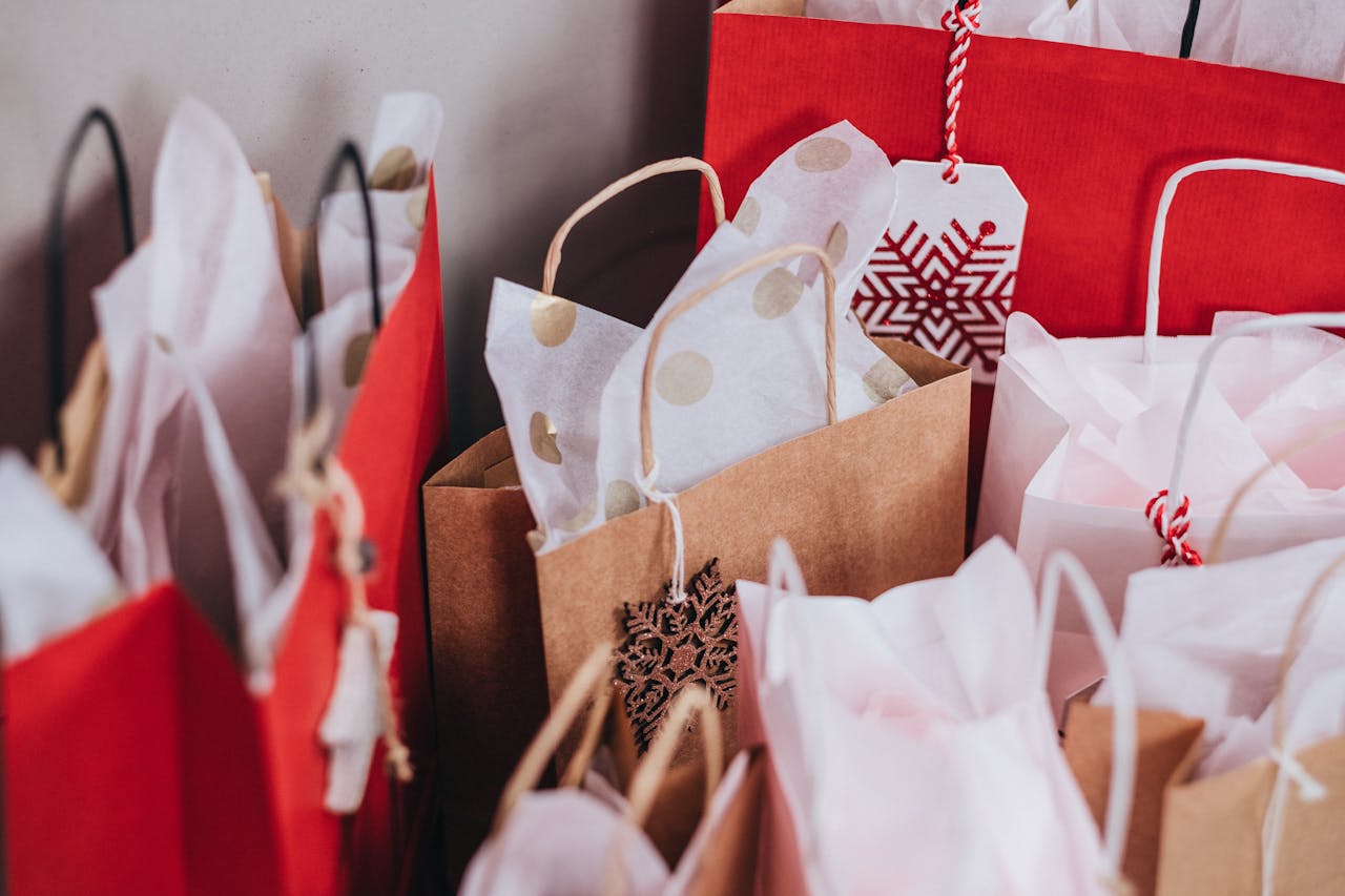 gallery-5 Collection of festive shopping bags filled with holiday gifts.